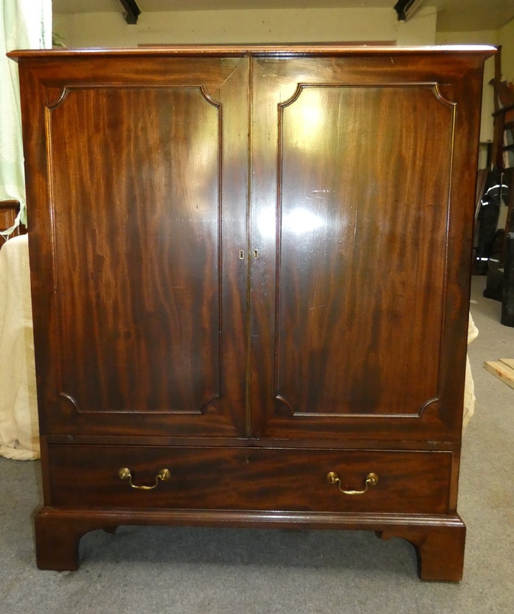 A Georgian mahogany dwarf press cupboard featuring twin panelled doors over a single drawer with brass handles. View II