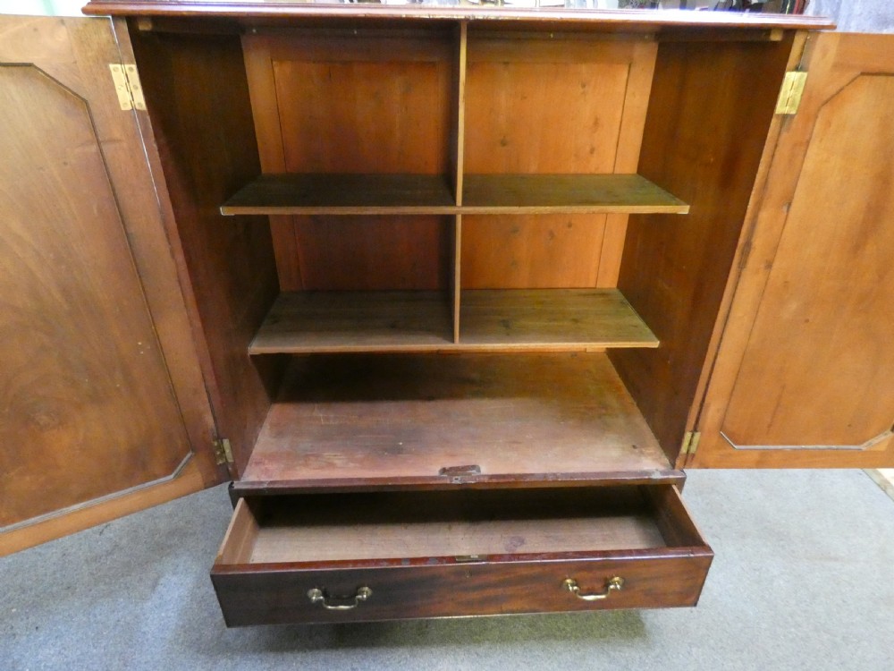 A Georgian mahogany dwarf press cupboard featuring twin panelled doors over a single drawer with brass handles. View VII