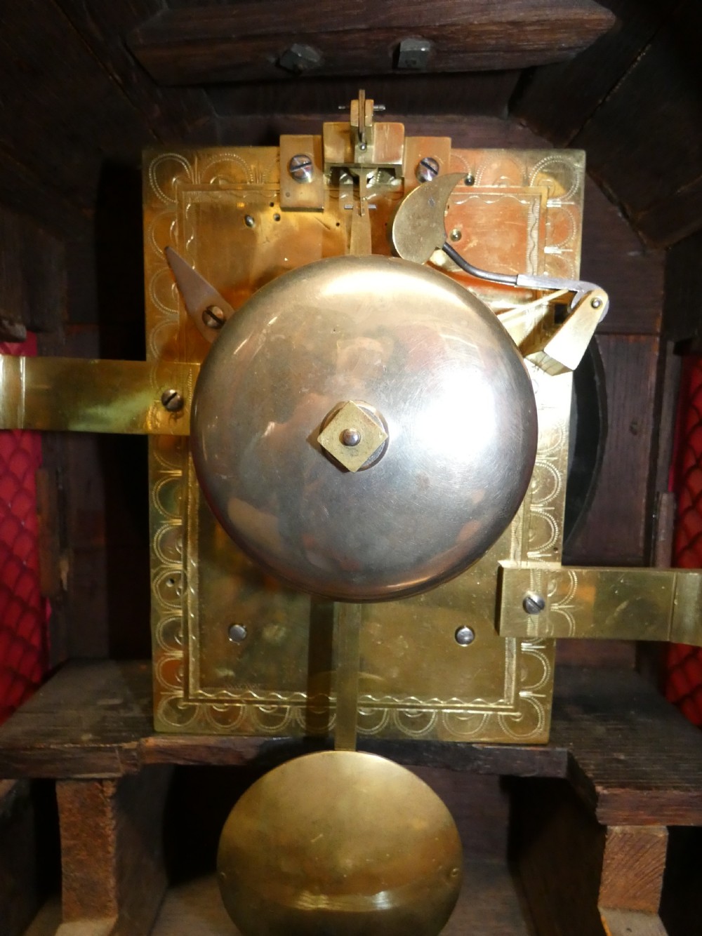 An antique dark mahogany bracket clock featuring an arched top with a brass carrying handle, a circular white dial signed Thos. Howard London, and brass fish-scale grilles. View VII