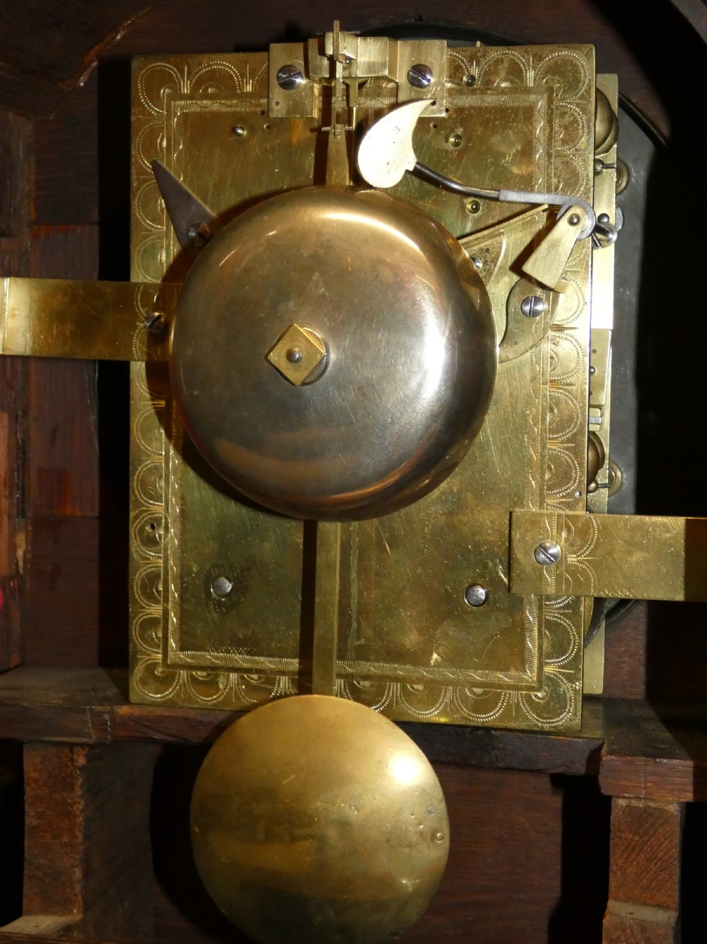 An antique dark mahogany bracket clock featuring an arched top with a brass carrying handle, a circular white dial signed Thos. Howard London, and brass fish-scale grilles. View IX