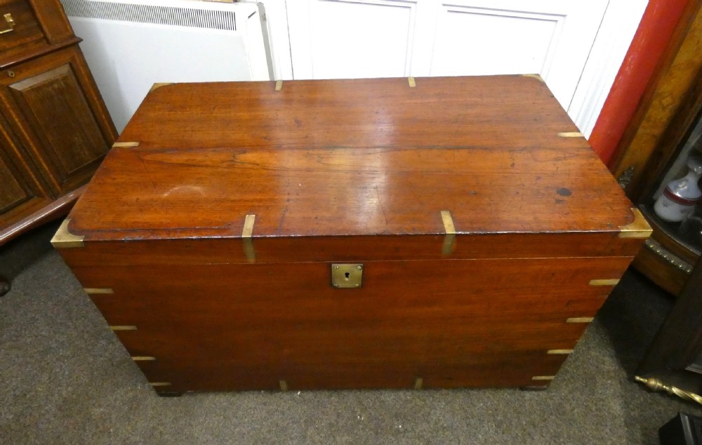 A rectangular warm brown mahogany military trunk featuring flush brass corner brackets, brass bindings, and a central keyhole escutcheon. View II