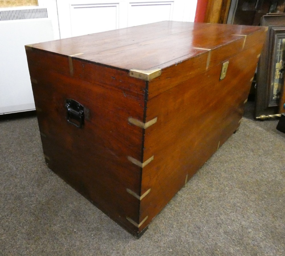 A rectangular warm brown mahogany military trunk featuring flush brass corner brackets, brass bindings, and a central keyhole escutcheon. View III