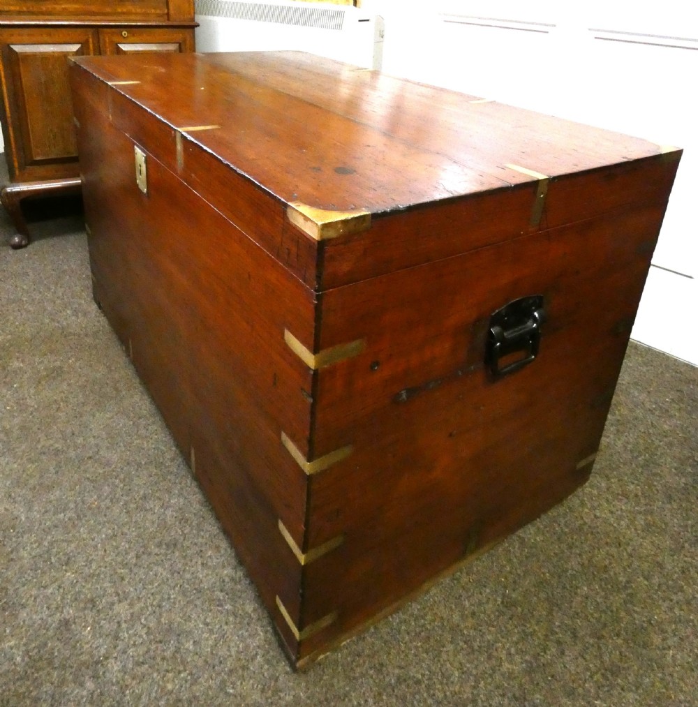 A rectangular warm brown mahogany military trunk featuring flush brass corner brackets, brass bindings, and a central keyhole escutcheon. View IV