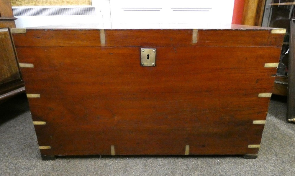 A rectangular warm brown mahogany military trunk featuring flush brass corner brackets, brass bindings, and a central keyhole escutcheon. View VI
