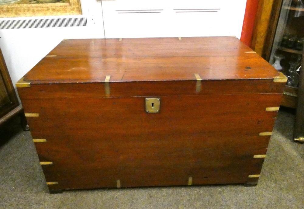 A rectangular warm brown mahogany military trunk featuring flush brass corner brackets, brass bindings, and a central keyhole escutcheon. View VII
