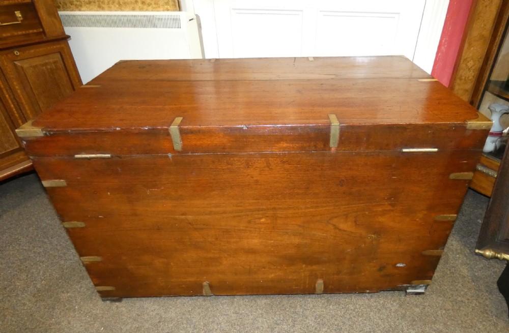 A rectangular warm brown mahogany military trunk featuring flush brass corner brackets, brass bindings, and a central keyhole escutcheon. View VIII