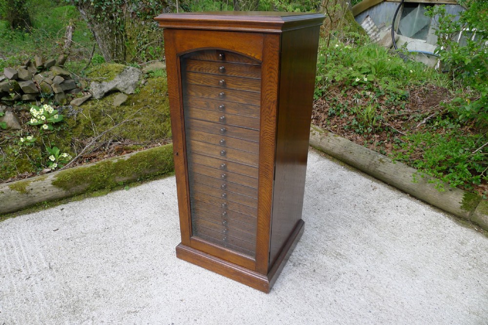 AN OAK 20 DRAWER COLLECTORS CABINET BY JANSEN OF LONDON CIRCA 1900.