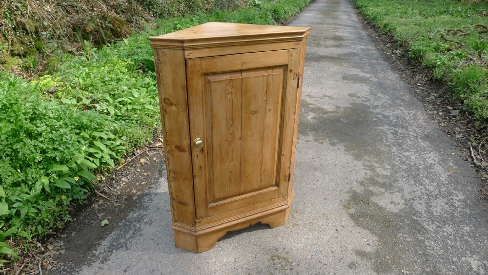 A GOOD COUNTRY PINE CORNER CUPBOARD ON BRACKET FEET. CIRCA 1850