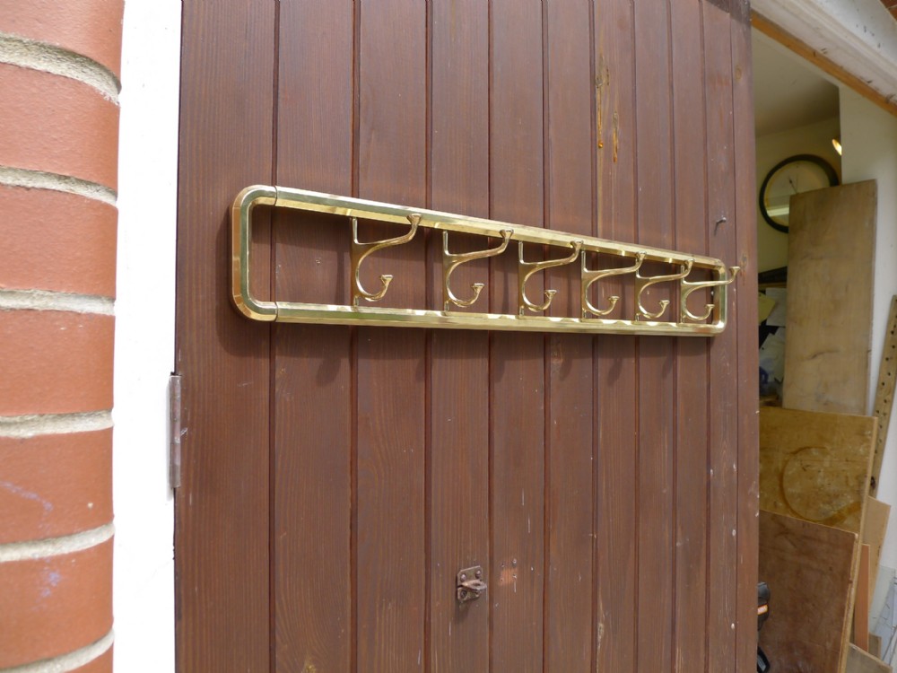 A SIX HOOK SWING OUT BRASS COAT AND HAT RACK. CIRCA 1910
