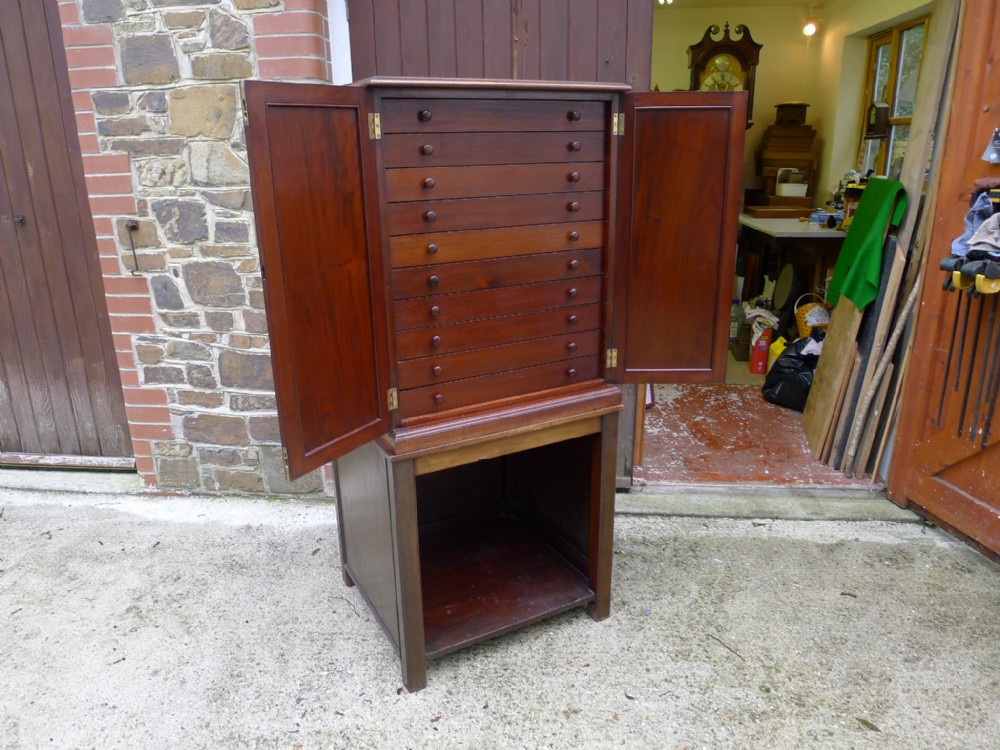 A 10 DRAWER MAHOGANY COLLECTORS CABINET ON STAND CIRCA 1920. BRADY STYLE DRAWERS.