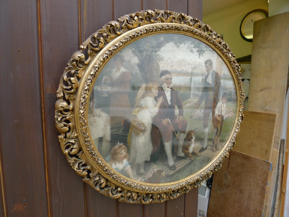 An ornate Victorian oval picture frame crafted from gilded gesso and timber, housing a glazed portrait print under glass.