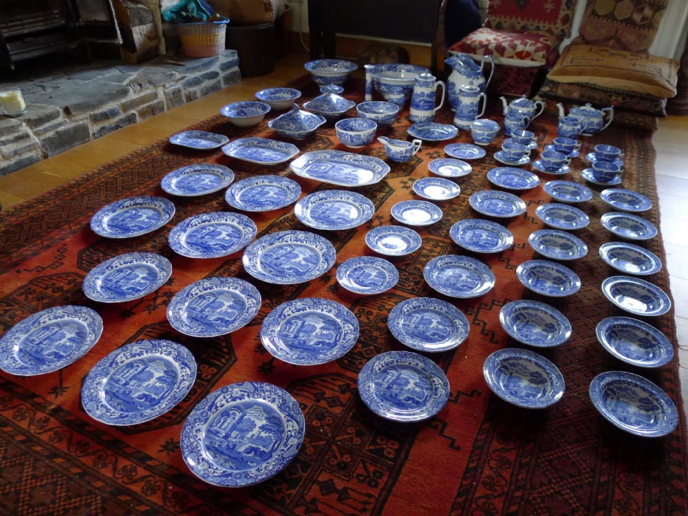 An extensive antique Copeland Spode Italian pattern blue and white earthenware dinner service laid out across a red patterned rug.