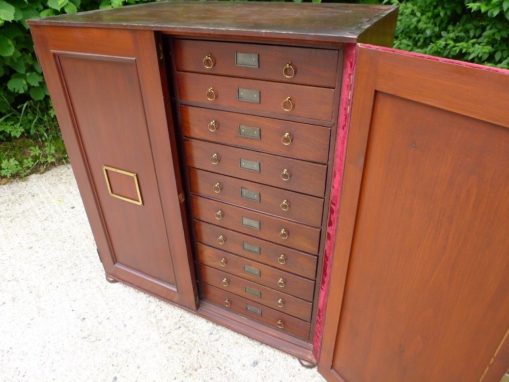 A mid-19th-century stained deal collectors cabinet featuring double doors opened to reveal twenty drawers with brass handles. View VII