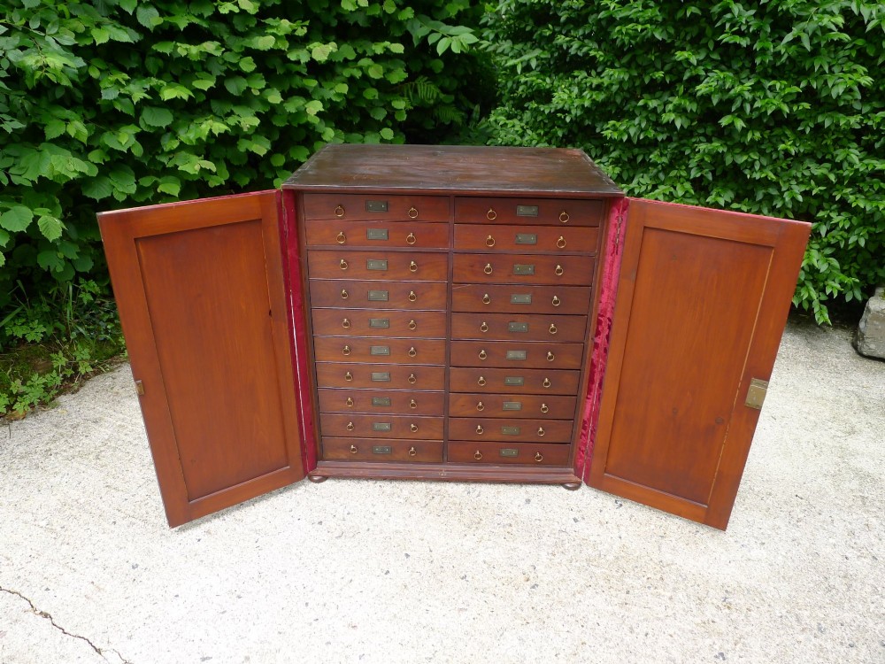 A mid-19th-century stained deal collectors cabinet featuring double doors opened to reveal twenty drawers with brass handles. View VIII