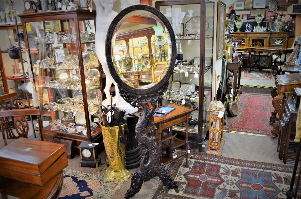 A 19th-century Chinese freestanding mirror featuring a circular glass face enclosed in a dark cherrywood frame carved with naturalistic prunus blossom branches. View II