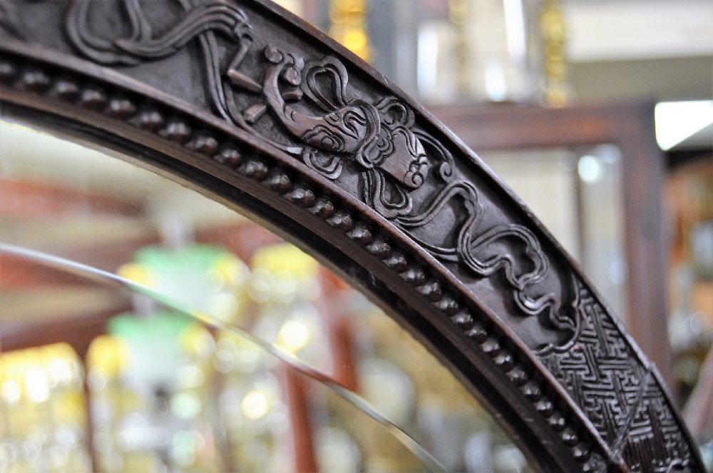 A 19th-century Chinese freestanding mirror featuring a circular glass face enclosed in a dark cherrywood frame carved with naturalistic prunus blossom branches. View IV