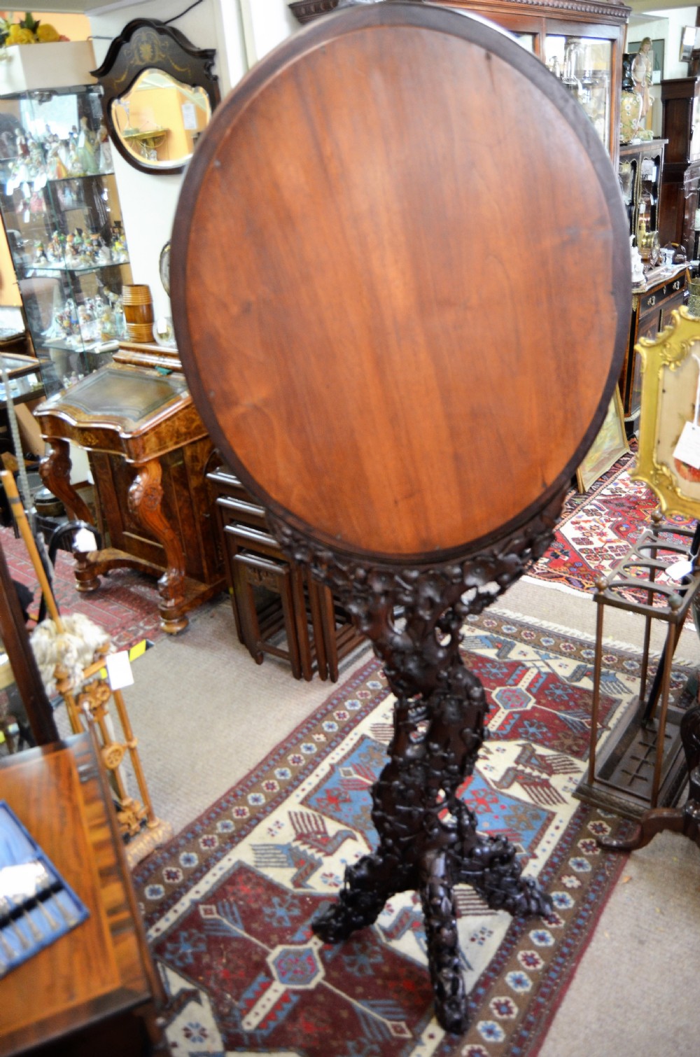 A 19th-century Chinese freestanding mirror featuring a circular glass face enclosed in a dark cherrywood frame carved with naturalistic prunus blossom branches. View VI