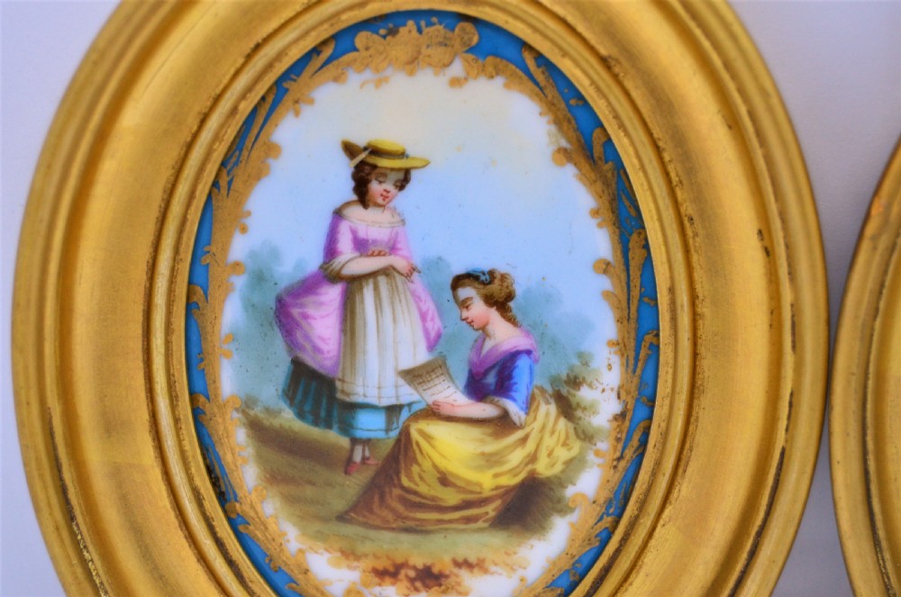 A pair of oval gilt-framed porcelain plaques featuring hand-painted pastoral figures within sky blue and gold scroll borders. View III