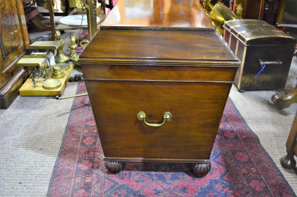 A Regency mahogany wine cooler featuring a sarcophagus shape, fluted corner pilasters, carved rosettes, a brass keyhole escutcheon, and gadrooned feet. View II