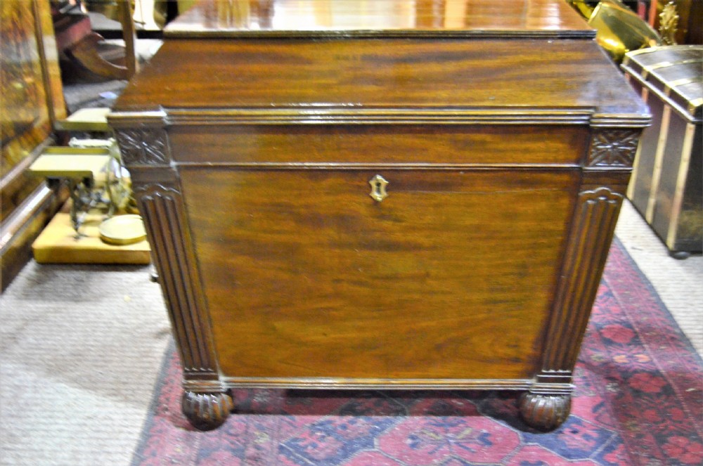 A Regency mahogany wine cooler featuring a sarcophagus shape, fluted corner pilasters, carved rosettes, a brass keyhole escutcheon, and gadrooned feet. View V