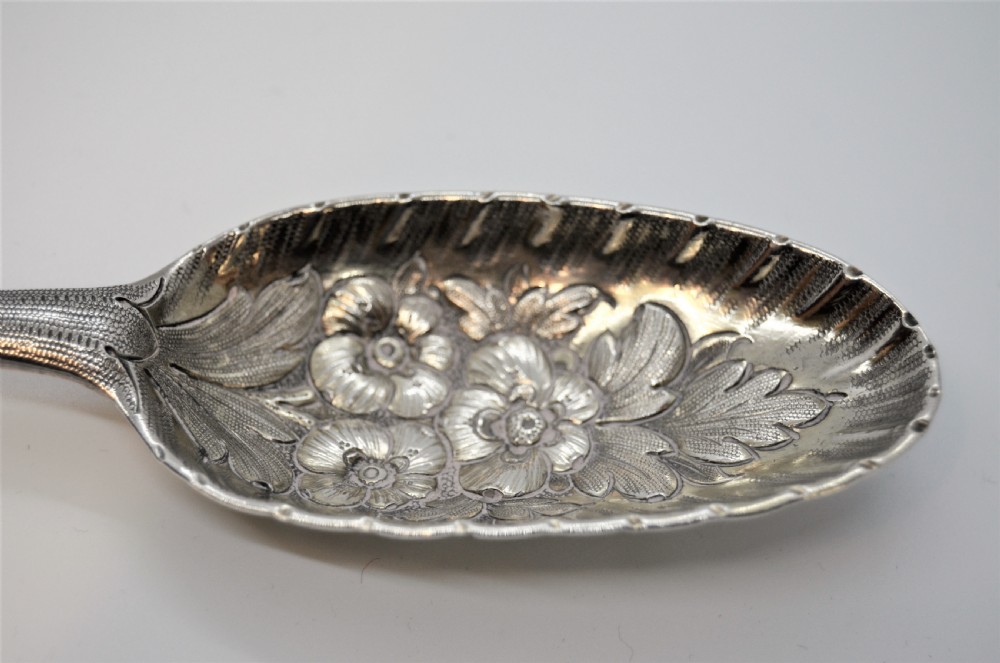 A pair of 18th-century Irish sterling silver spoons featuring embossed fruit and leaf designs in the bowls and chased pattern handles. View V