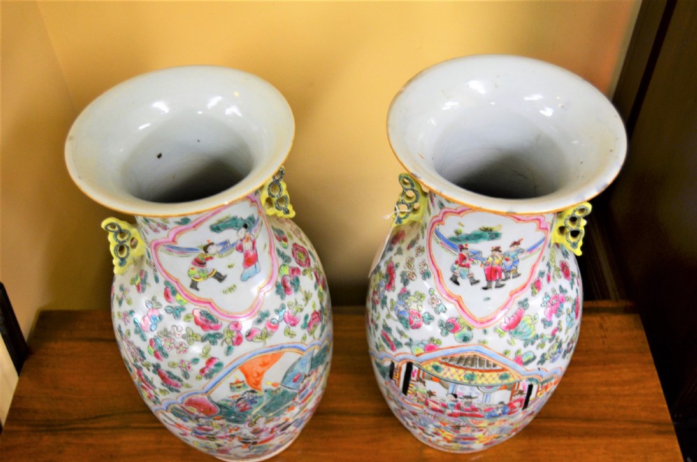 A pair of 19th-century Chinese Famille Rose porcelain baluster vases decorated with hand-painted narrative scenes inside cartouches and yellow pierced handles. View V