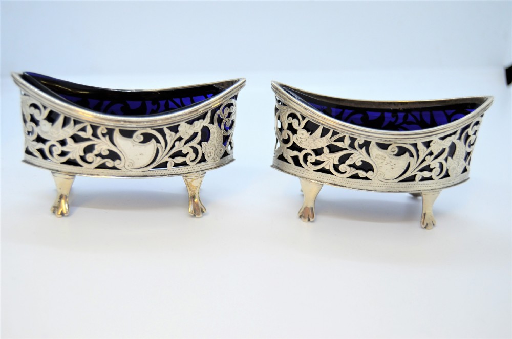 A pair of pierced silver open salt cellars raised on claw feet and fitted with deep cobalt blue glass liners.