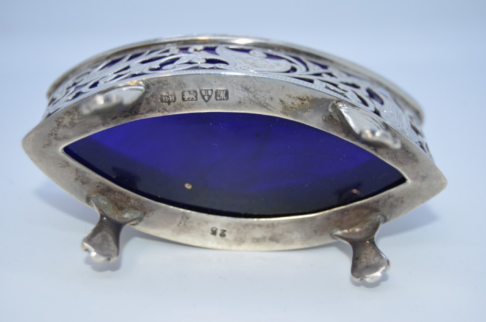 A pair of pierced silver open salt cellars raised on claw feet and fitted with deep cobalt blue glass liners. View V