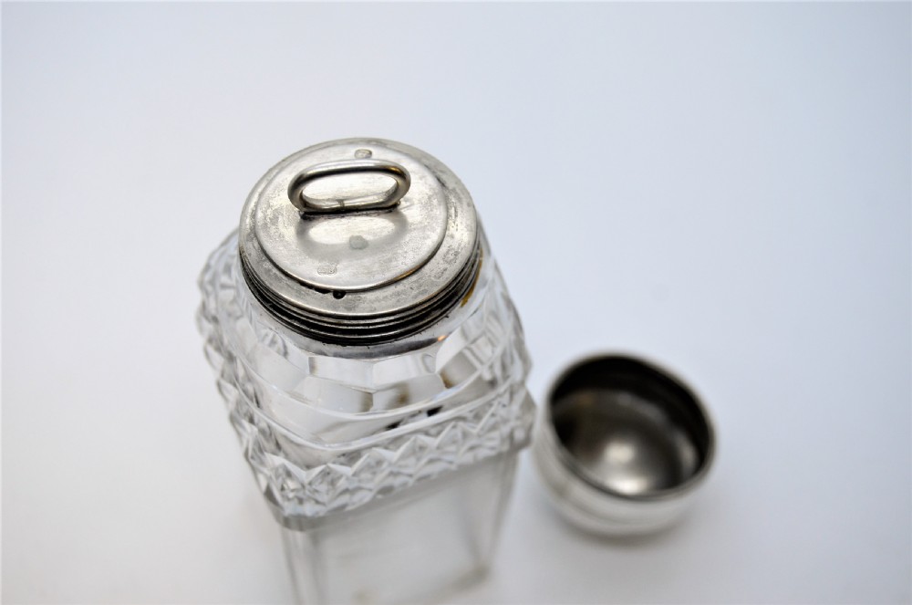 A Georgian silver cruet frame holding four square cut glass condiment bottles with silver domed caps and a central loop handle. View IV