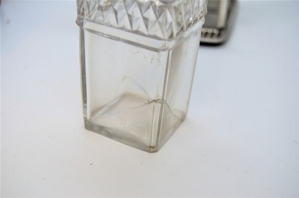 A Georgian silver cruet frame holding four square cut glass condiment bottles with silver domed caps and a central loop handle. View V