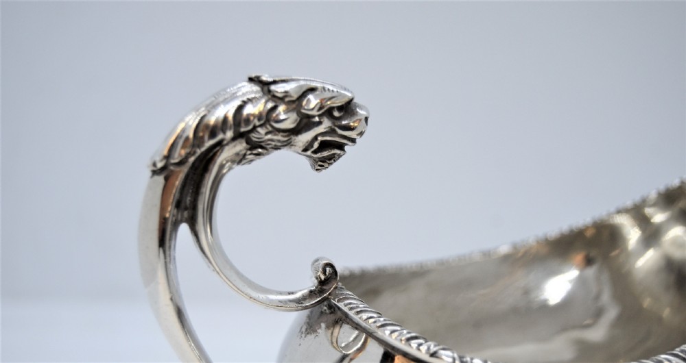 A polished sterling silver sauce boat featuring a serpent head handle, gadrooned rim, and three lion mask feet with visible hallmarks. View III