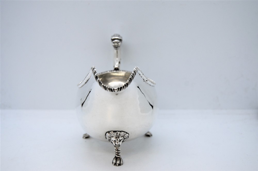 A polished sterling silver sauce boat featuring a serpent head handle, gadrooned rim, and three lion mask feet with visible hallmarks. View V