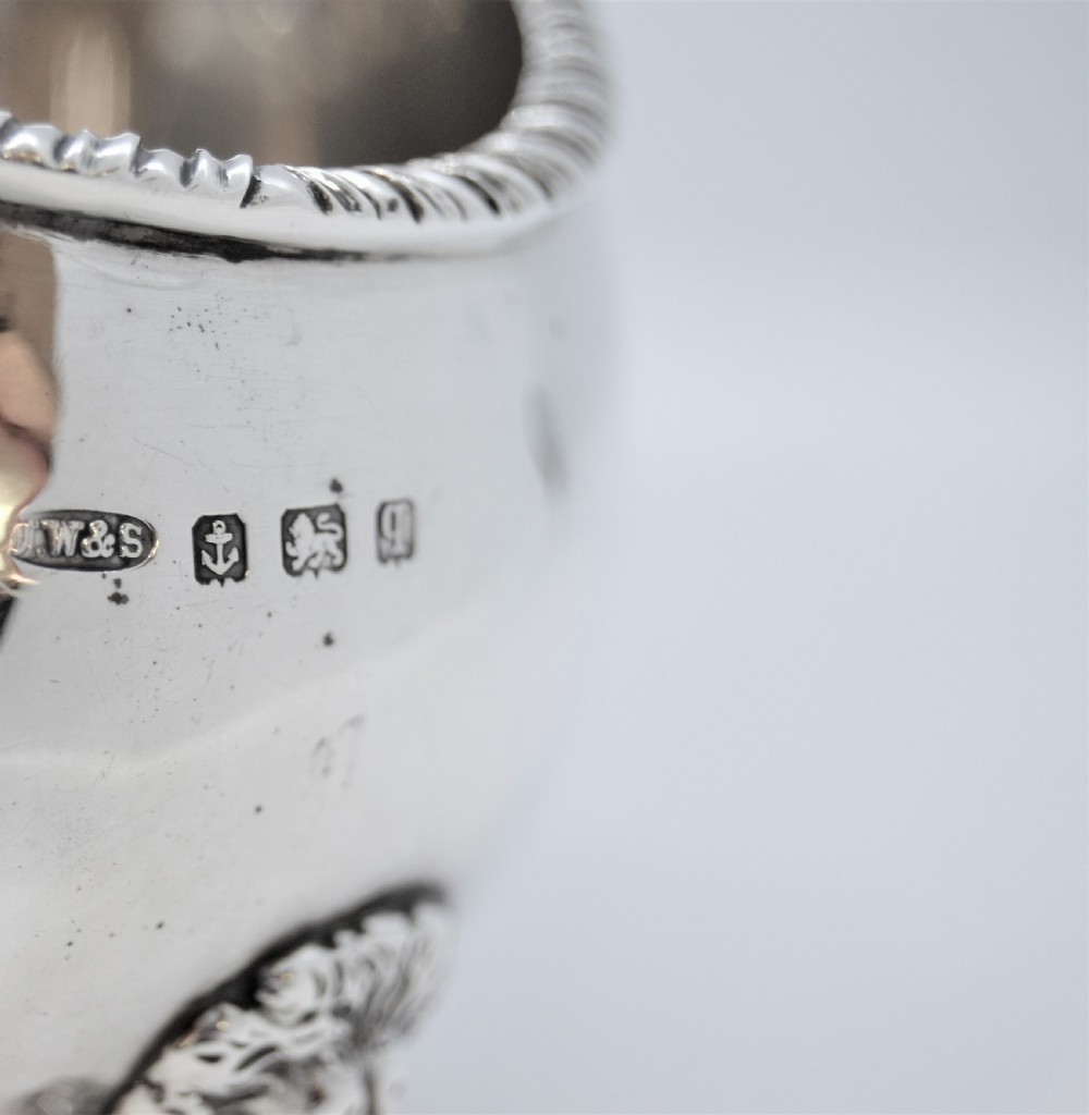 A polished sterling silver sauce boat featuring a serpent head handle, gadrooned rim, and three lion mask feet with visible hallmarks. View VI