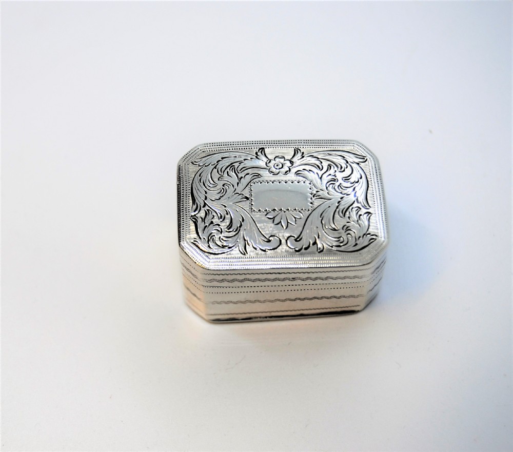 An engraved rectangular Georgian sterling silver nutmeg grater box with canted corners and acanthus leaf engraving.