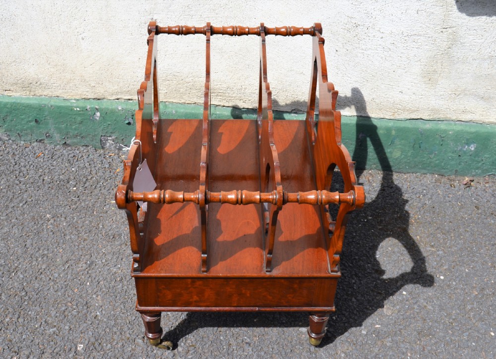 A Victorian mahogany canterbury featuring three carved slotted compartments, a lower drawer with a turned knob, and turned legs with brass castors. View III