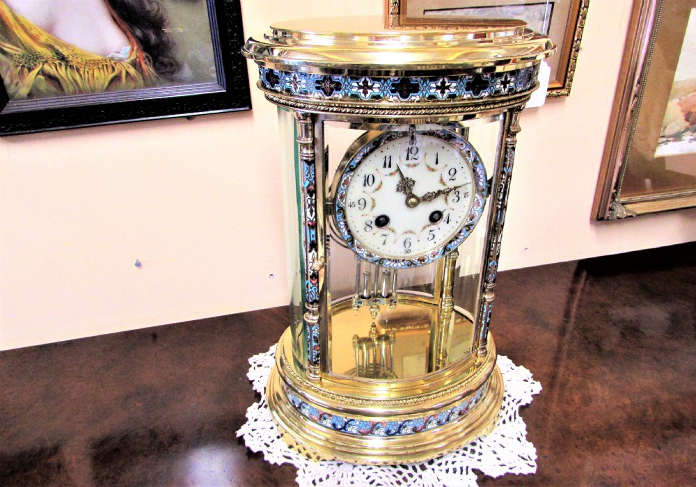 An oval Victorian brass four glass mantel clock featuring colourful cloisonne enamel floral borders and a porcelain dial. View II