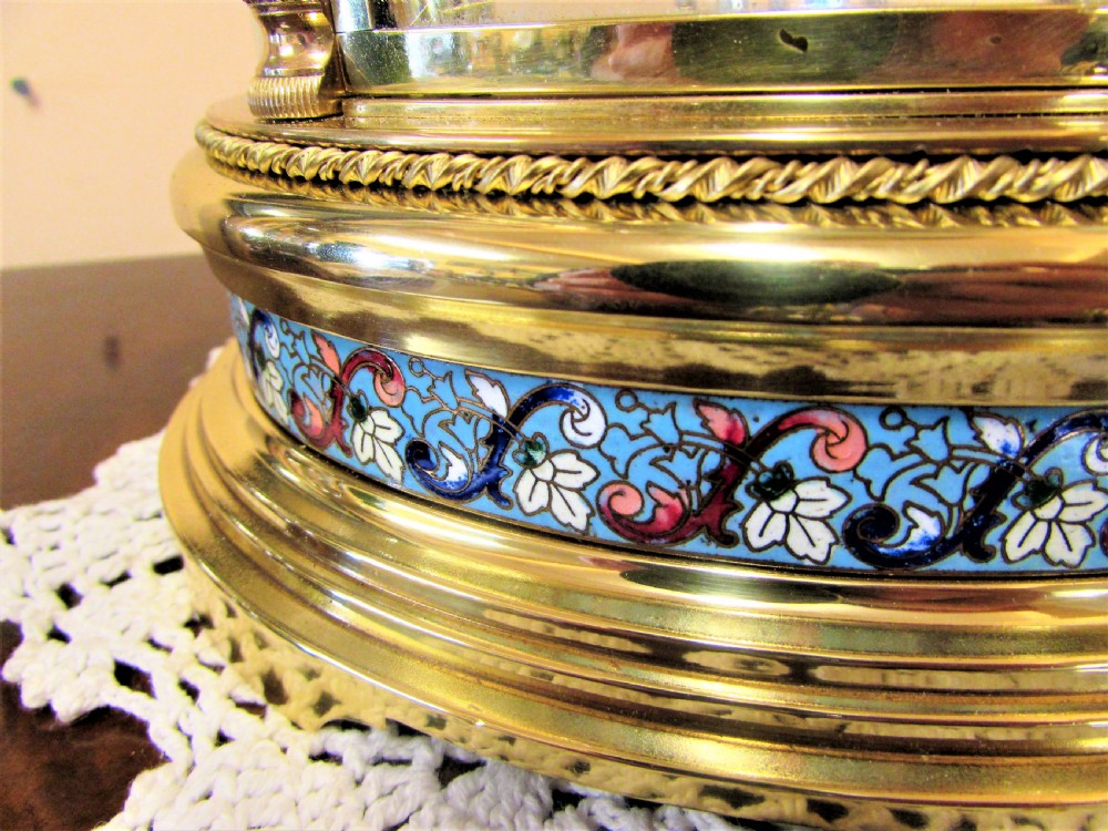 An oval Victorian brass four glass mantel clock featuring colourful cloisonne enamel floral borders and a porcelain dial. View III