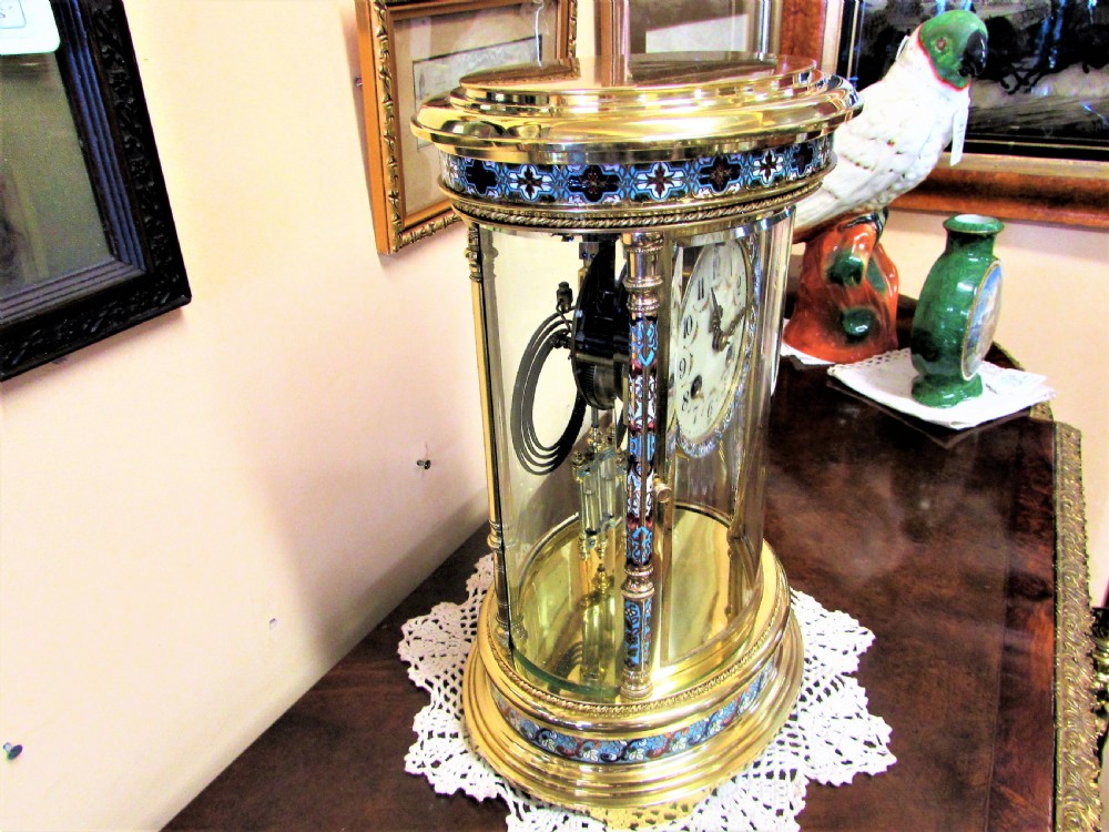 An oval Victorian brass four glass mantel clock featuring colourful cloisonne enamel floral borders and a porcelain dial. View V