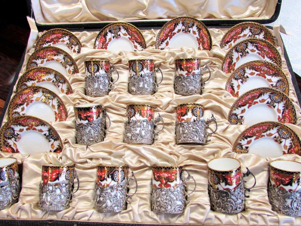 A cased set of Royal Crown Derby porcelain demitasse coffee cups with pierced silver holders and matching saucers in a satin-lined presentation box.