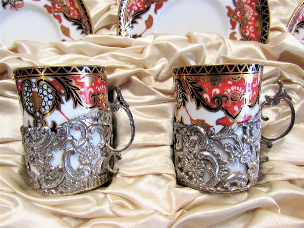 A cased set of Royal Crown Derby porcelain demitasse coffee cups with pierced silver holders and matching saucers in a satin-lined presentation box. View II