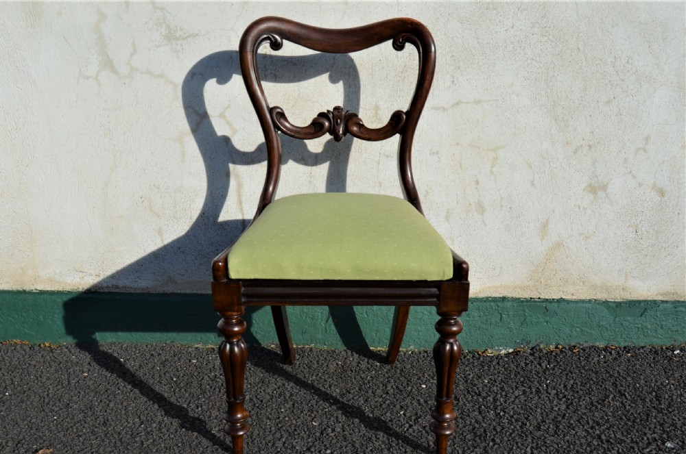 A set of six Victorian rosewood balloon-back dining chairs featuring carved cross-rails, turned front legs, and light green upholstered seats. View II