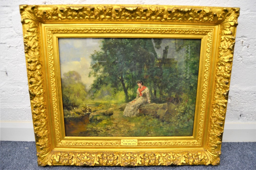 A Victorian oil painting depicting a woman seated beside a stream in a forested landscape, enclosed within an ornate carved gilt frame.