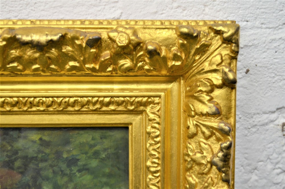 A Victorian oil painting depicting a woman seated beside a stream in a forested landscape, enclosed within an ornate carved gilt frame. View III
