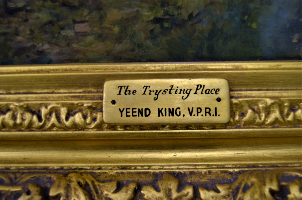 A Victorian oil painting depicting a woman seated beside a stream in a forested landscape, enclosed within an ornate carved gilt frame. View V