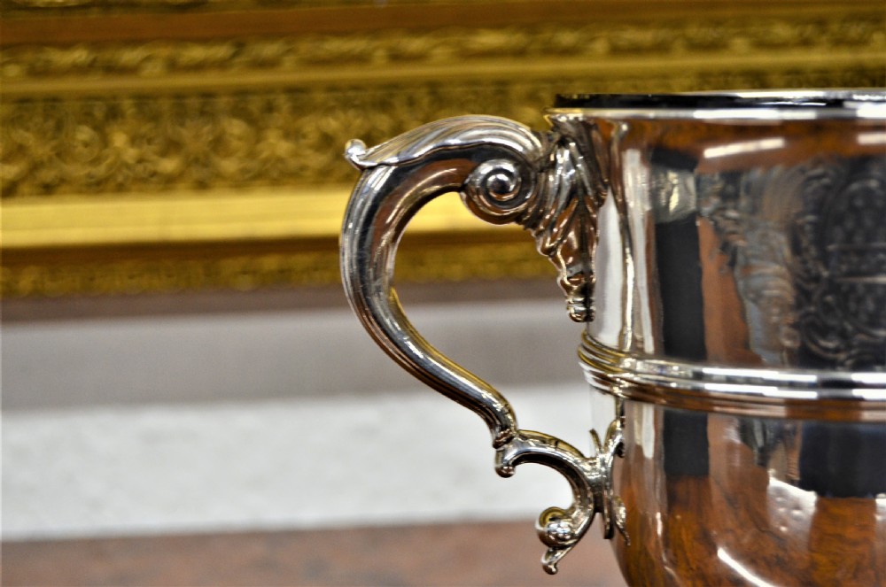 An 18th-century silver two-handled cup featuring an engraved crest, double-scroll handles, a central moulding, and a circular pedestal foot. View III