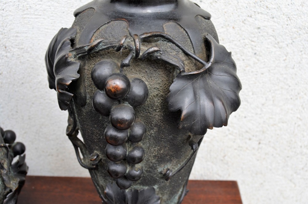 A pair of dark patinated bronze vases decorated with high-relief carved grapevine motifs and fruit clusters over a textured surface. View III