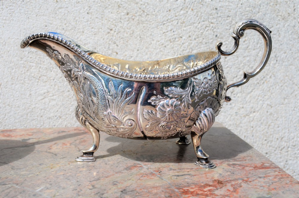 A matching pair of silver sauce boats featuring ornate floral repousse chasing, double-scroll handles, and shell-capped pad feet. View II