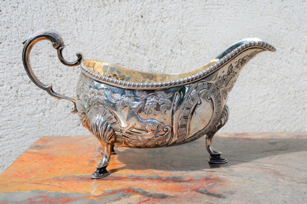 A matching pair of silver sauce boats featuring ornate floral repousse chasing, double-scroll handles, and shell-capped pad feet. View III