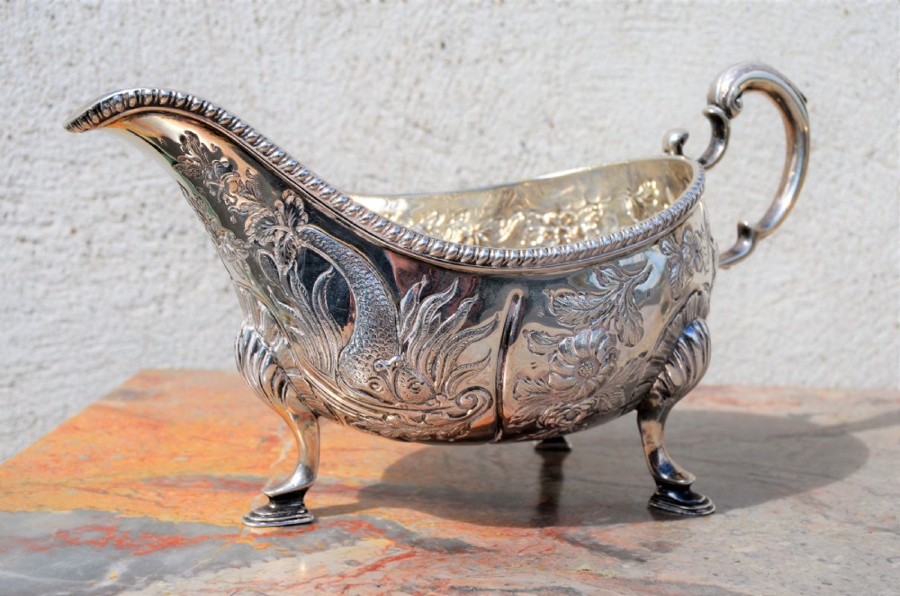 A matching pair of silver sauce boats featuring ornate floral repousse chasing, double-scroll handles, and shell-capped pad feet. View IV