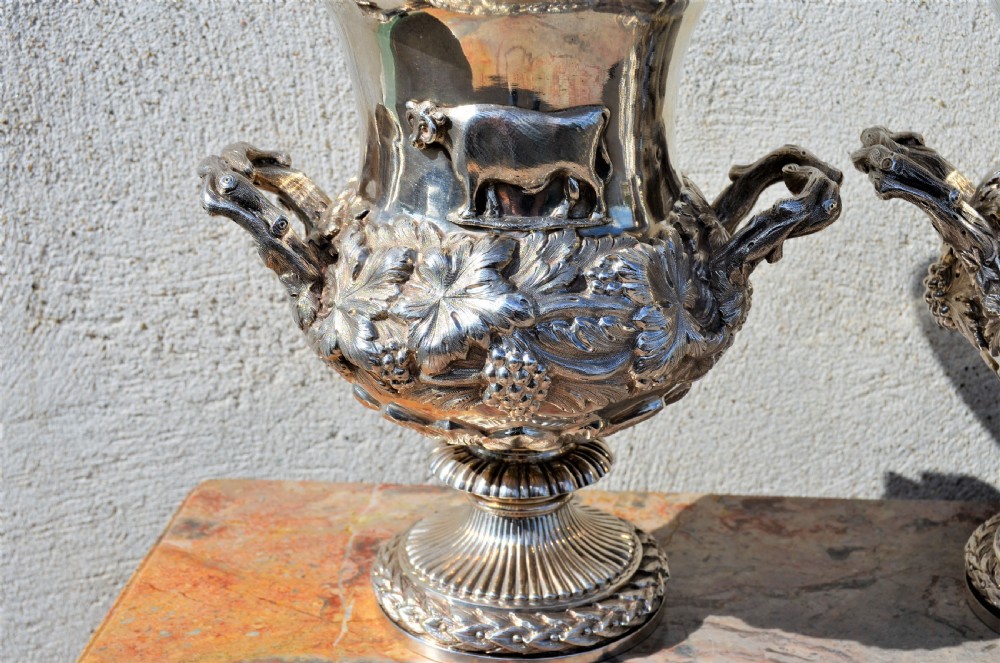 A pair of silver twin-handled urn-shaped vases featuring raised grapevine ornamentation, branch-form handles, and fluted pedestal bases. View VI